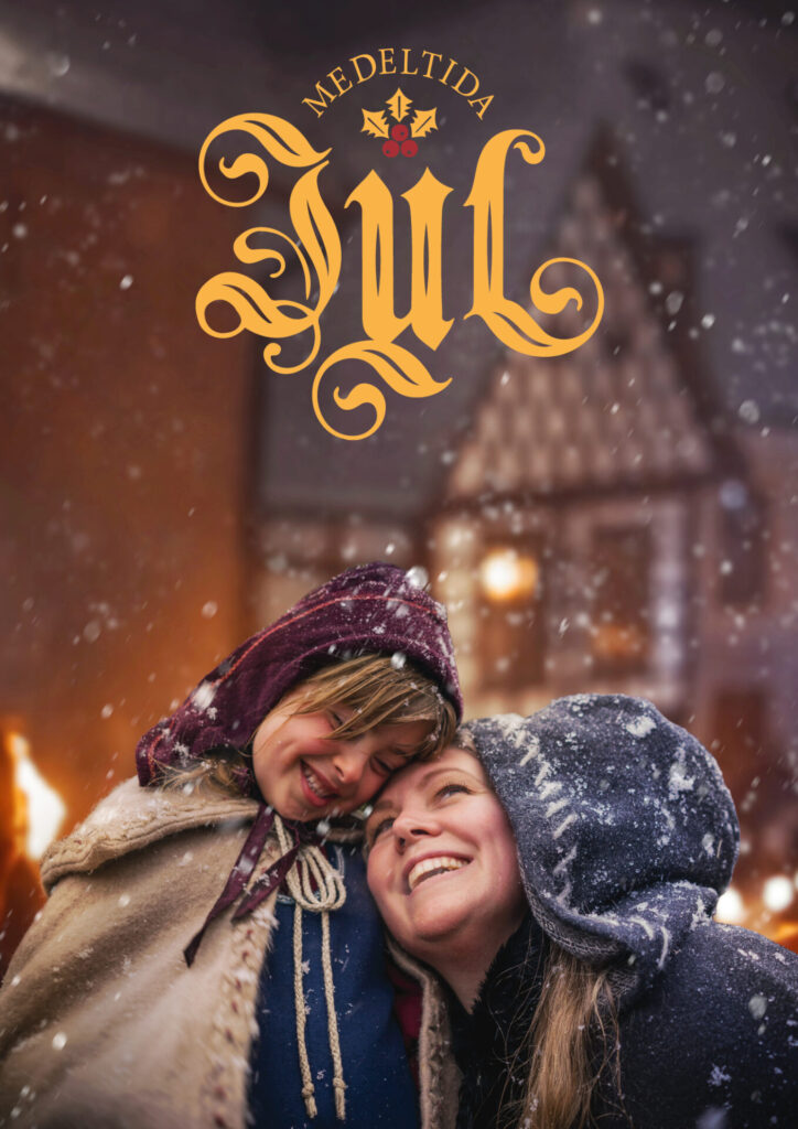 Mor och dotter i medeltidskläder ler och njuter av ett snöfall i Visby.